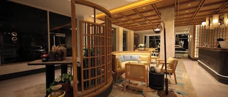 A modern interior with a reception desk, seating area, and a decorative partition.
