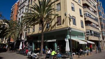 Un edificio de varios pisos con terraza al aire libre y palmeras.