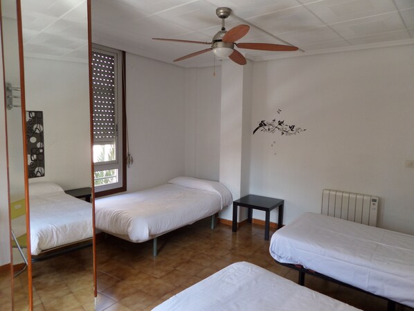 A room with two single beds, a ceiling fan, a radiator, and a window with blinds. - Russafa Youth Hostel (Valencia)