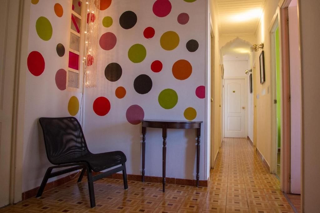 A hallway with a polka dot wall, a chair, and a small table.