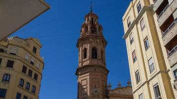 Un campanario con veleta en la parte superior, rodeado de edificios.