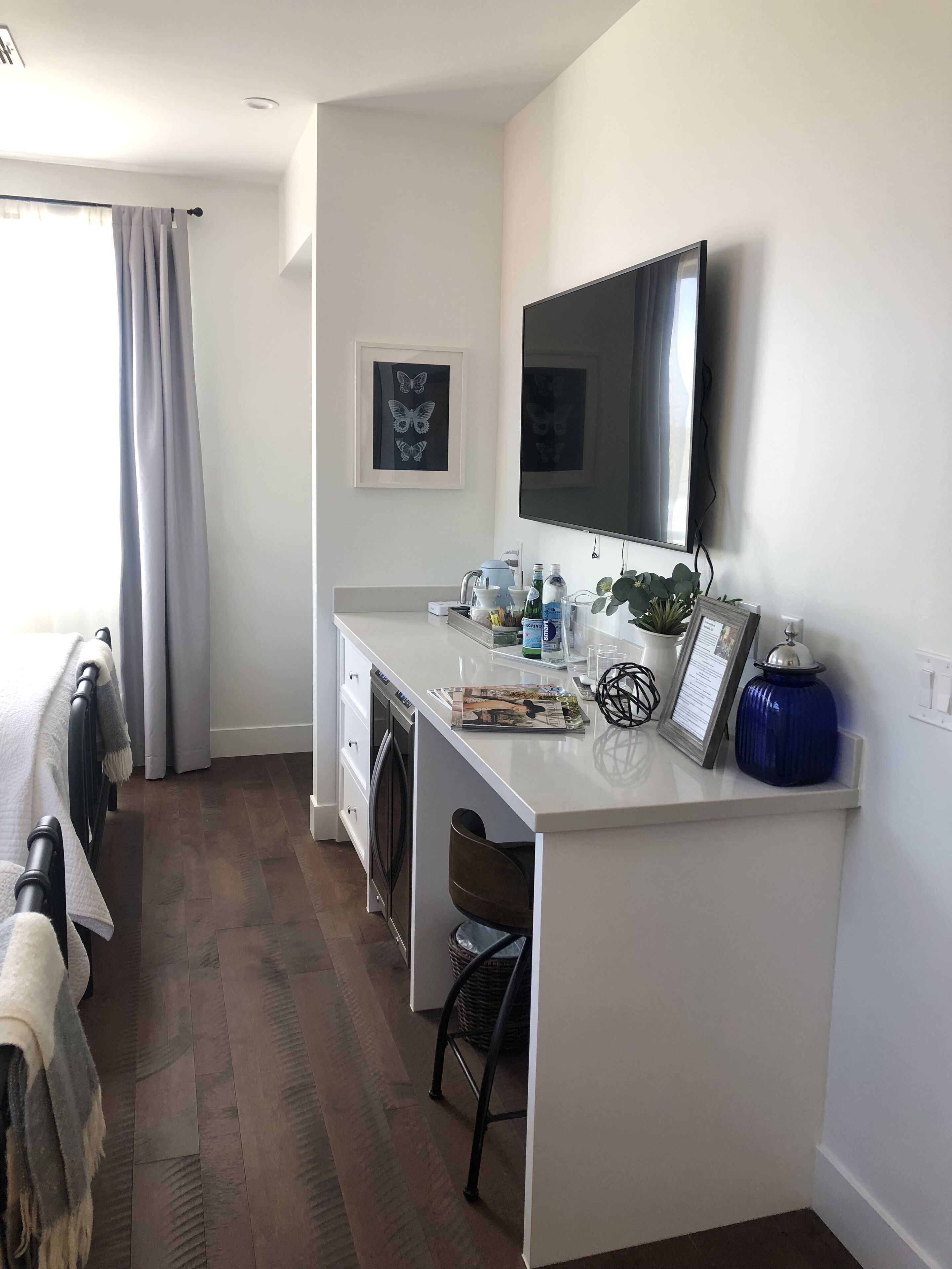 A modern kitchen with a built-in oven, a dining area with a table and chairs, and a large flat-screen TV mounted above the counter.