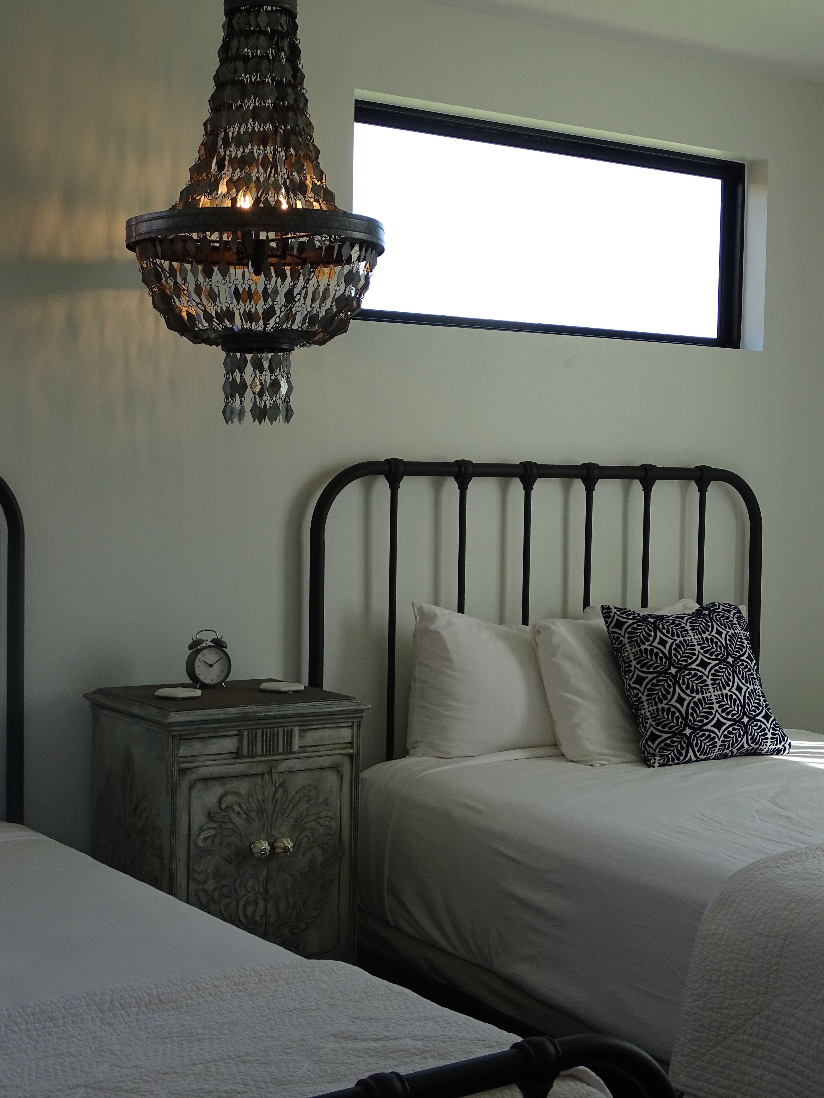 Quarto com cama, mesa de cabeceira e um lustre decorativo.
