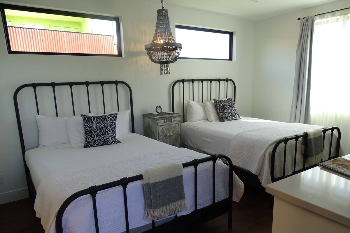 A bedroom with two beds, a nightstand, a dresser, and a chandelier.