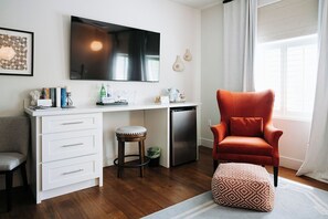 A modern kitchen with a white countertop, a built-in oven, and a red chair.