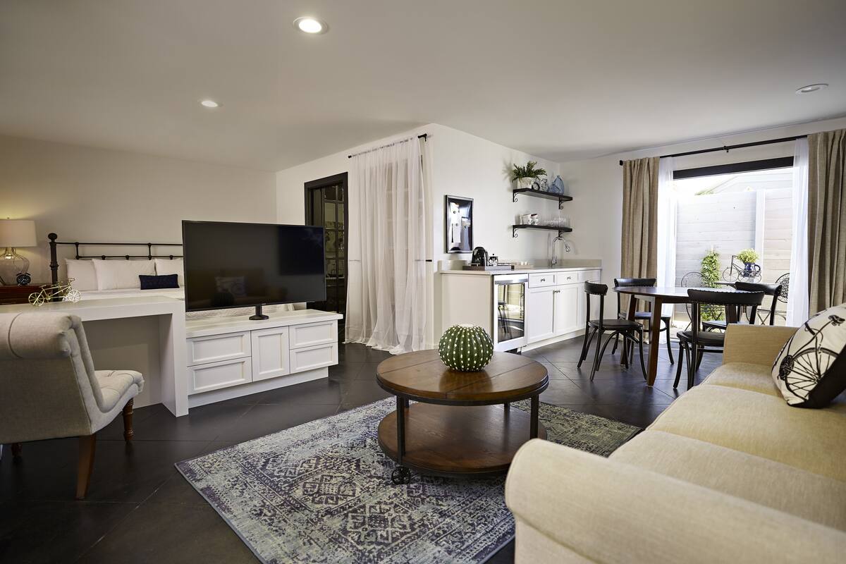 A modern living room with a TV, sofa, coffee table, and dining area.