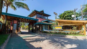 A hotel entrance with a covered walkway, a signboard, and a wooden structure with a roof. - Hotel Pousada Tambayba (Sao Sebastiao)