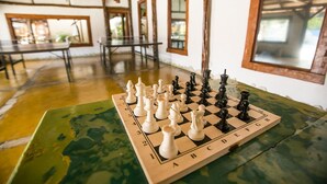 A chessboard on a table in a room with wooden beams and large windows. - Hotel Pousada Tambayba (Sao Sebastiao)
