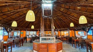 A spacious restaurant with a high wooden ceiling, hanging pendant lights, and a central island with seating around it. - Hotel Pousada Tambayba (Sao Sebastiao)