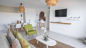 Una sala de estar moderna con sofá, sillones, una mesa de centro y un televisor montado en la pared.