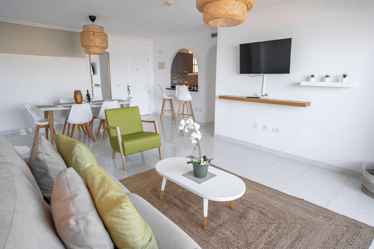 A modern living room with a sofa, chairs, a coffee table, and a TV mounted on the wall.