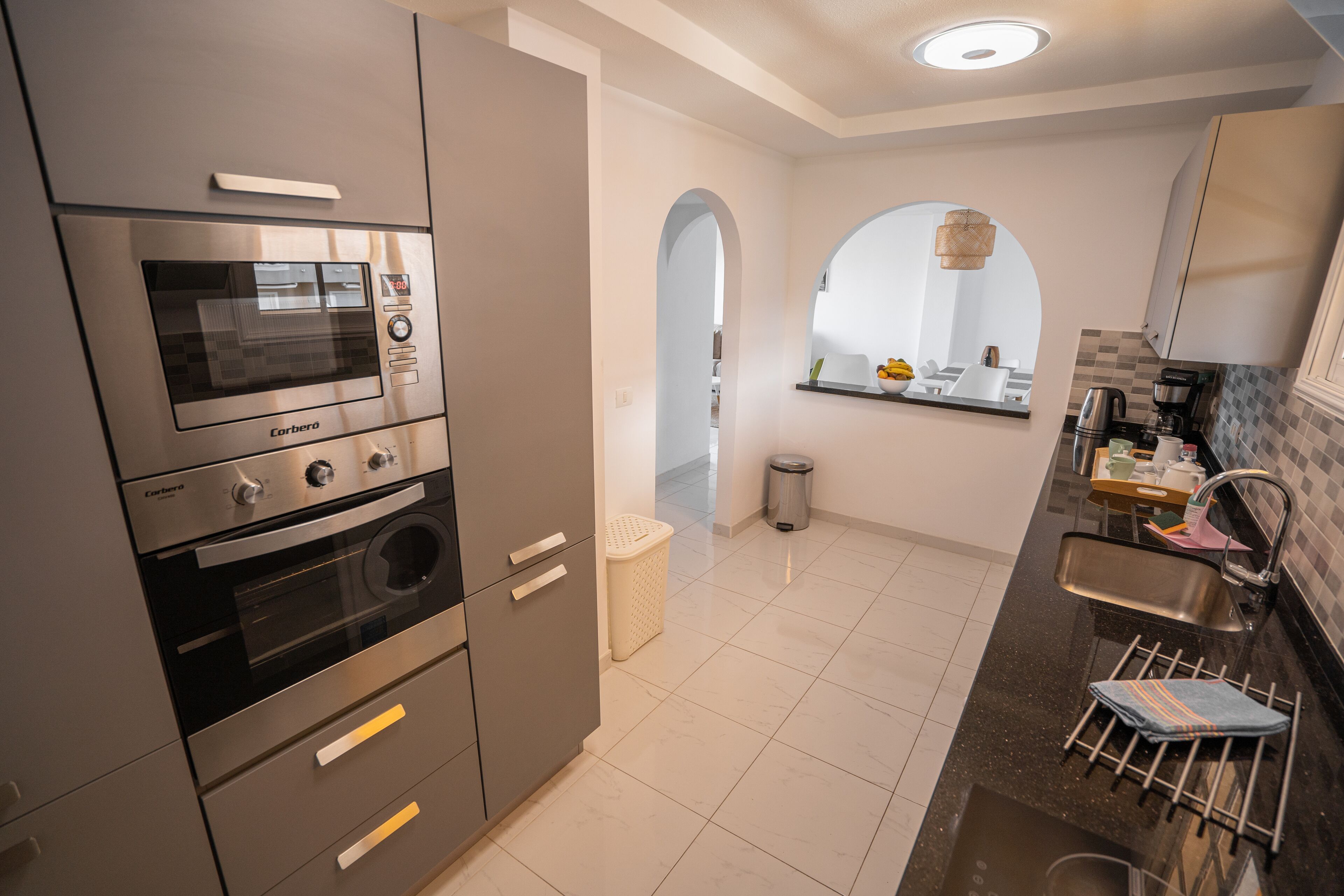 A modern kitchen with stainless steel appliances, a built-in oven, and a sink with a drying rack.