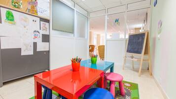 Learn and play in this vibrant classroom setting with a red table, blue chair, and pink stool.