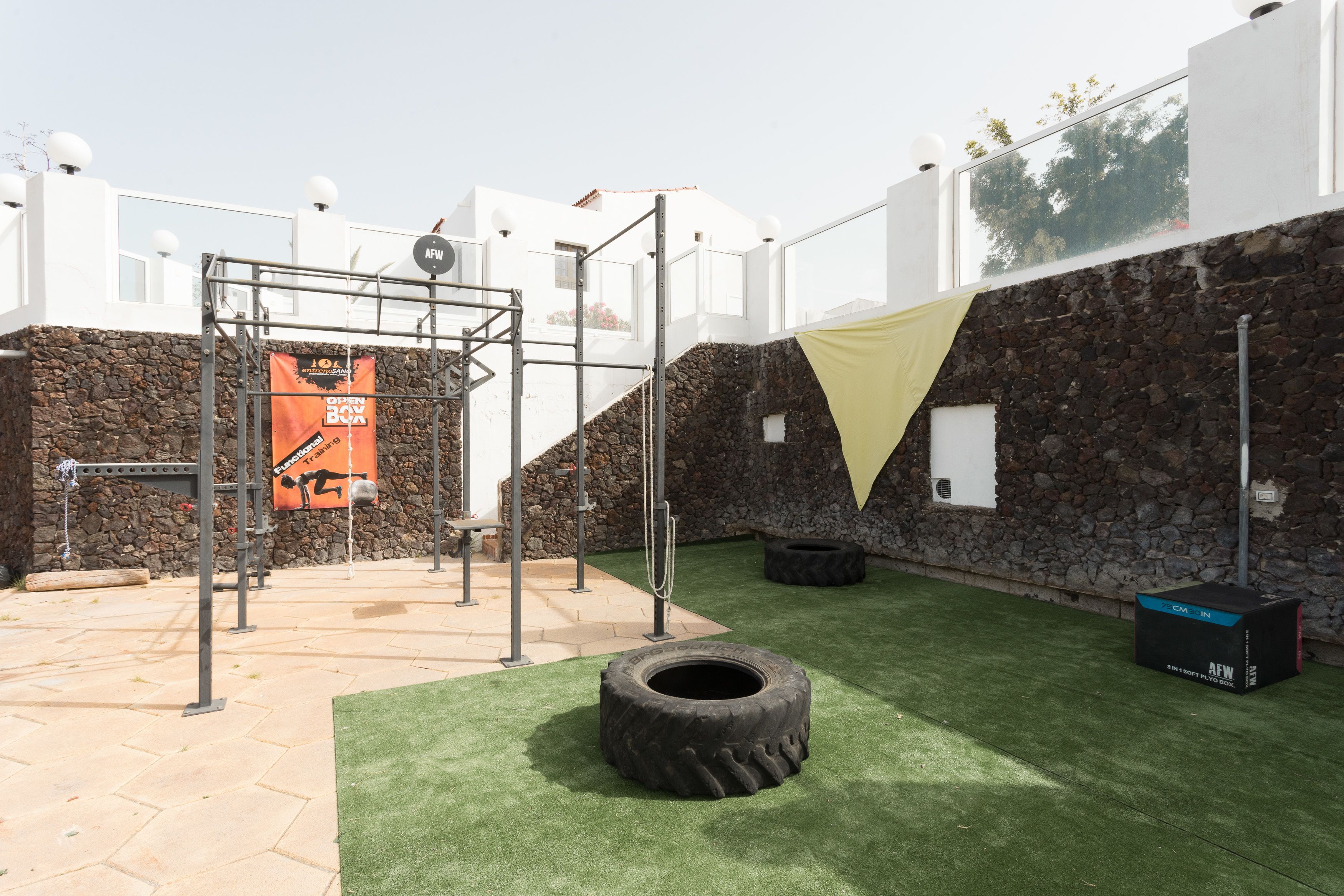 An outdoor gym area with a pull-up bar, tire, and a banner for an event.