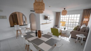 Una sala moderna con comedor, un sofá y un televisor montado en la pared.