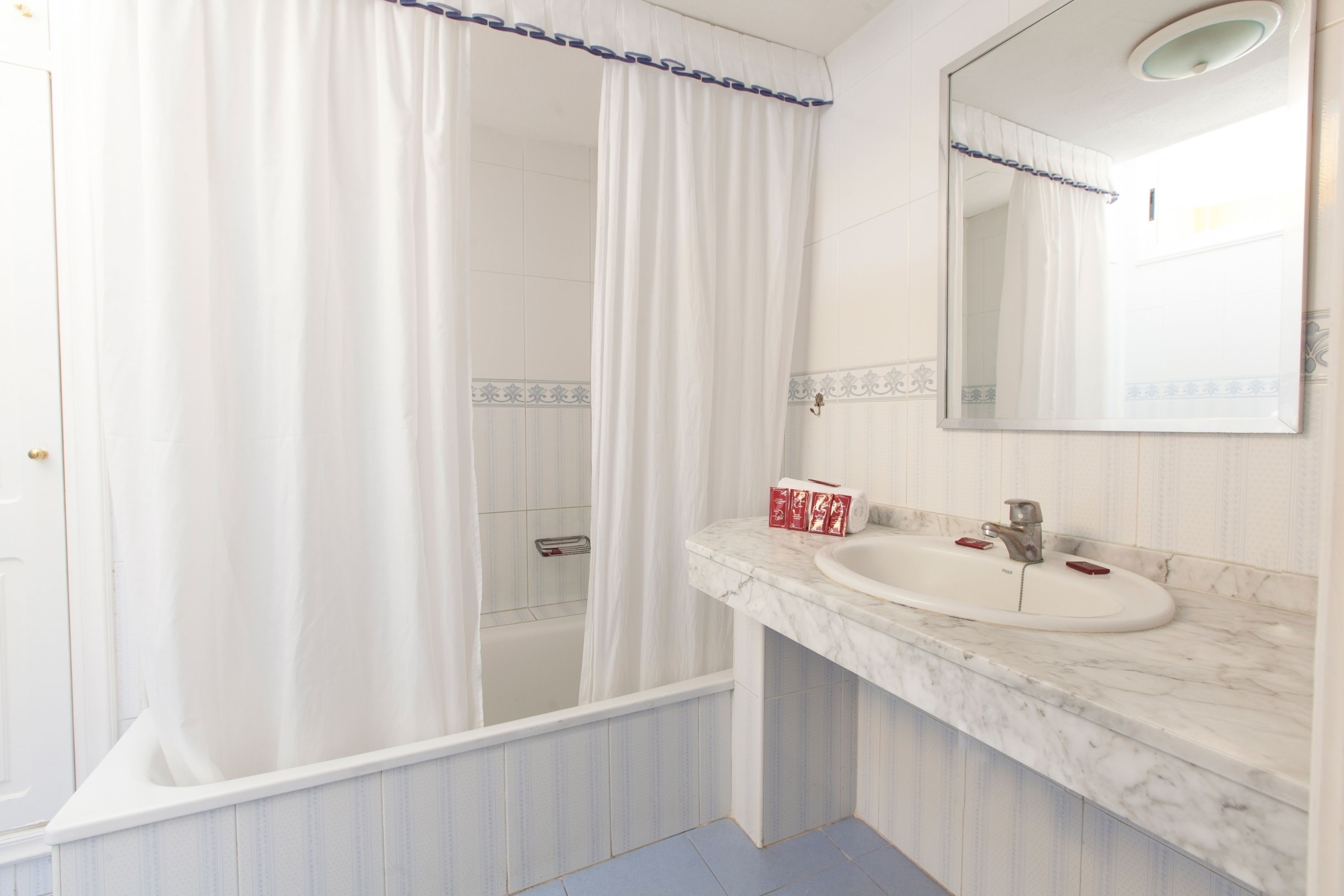 Un baño con cortina de ducha, lavabo y espejo.