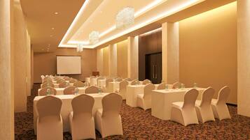 A conference room with multiple tables and chairs, a projector screen, and a large screen.