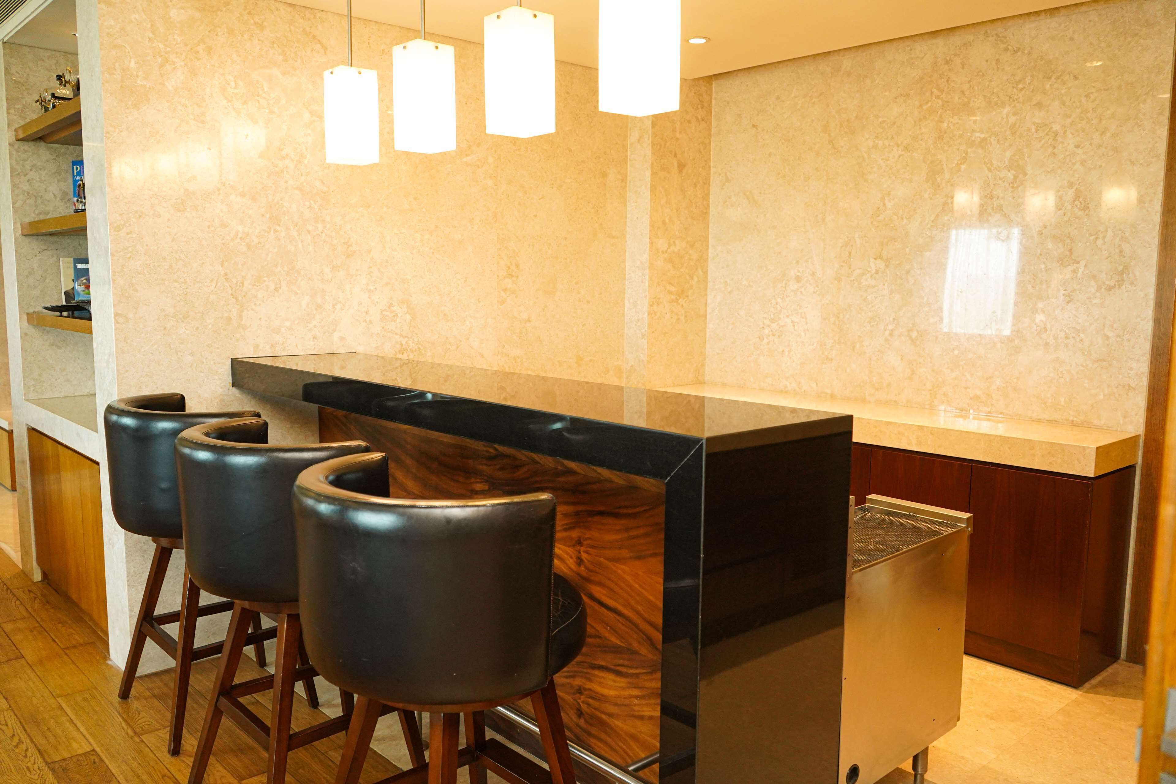 Une cuisine moderne avec un plan de travail en marbre, des tabourets de bar noirs et des luminaires suspendus.