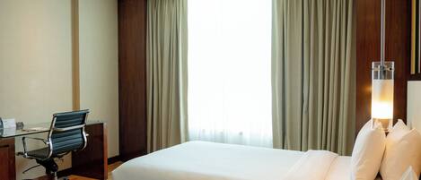 A hotel room with two beds, a desk, and a chair.