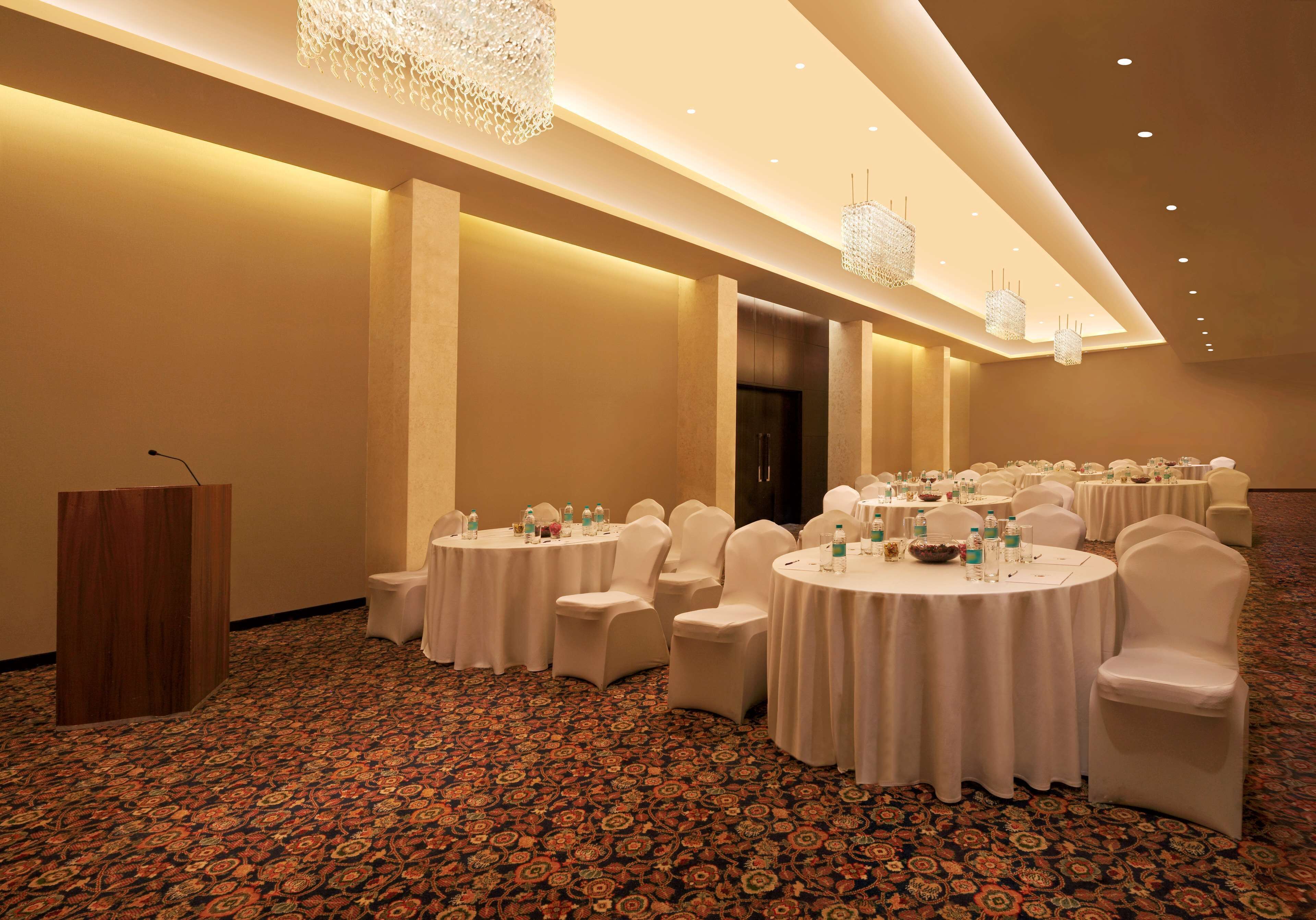 A conference room with round tables, white chairs, and a podium.