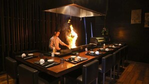 A restaurant with a central cooking station featuring a fire, surrounded by tables with neatly set dining ware. - Doubletree By Hilton Pune - Chinchwad (Pune)