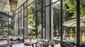 A spacious indoor dining area with large windows, black-framed tables, and white chairs. - Palazzo Parigi Hotel & Grand Spa Milan (Milan)