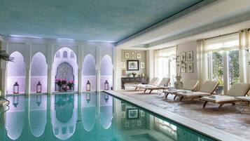 A swimming pool with lounge chairs and a decorative wall with arches.