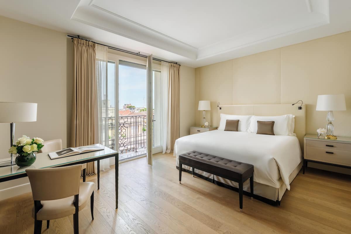 Ein Hotelzimmer mit einem Bett, Nachttischen, einem Schreibtisch mit Stuhl, einem Fenster mit Vorhängen und Blick nach draußen.