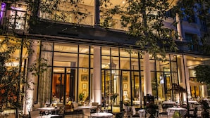 An outdoor dining area with tables and chairs, large windows, and columns. - Palazzo Parigi Hotel & Grand Spa Milan (Milan)