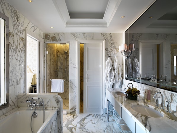 Une salle de bain luxueuse avec un grand lavabo en marbre, une baignoire et une douche à l’italienne.