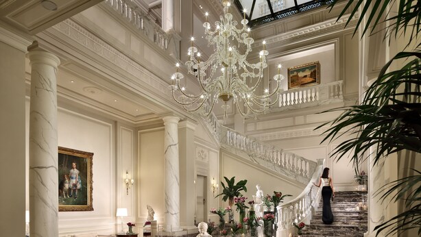 A grand lobby with marble columns, a chandelier, a staircase, and a statue. - Palazzo Parigi Hotel & Grand Spa Milan (Milan)