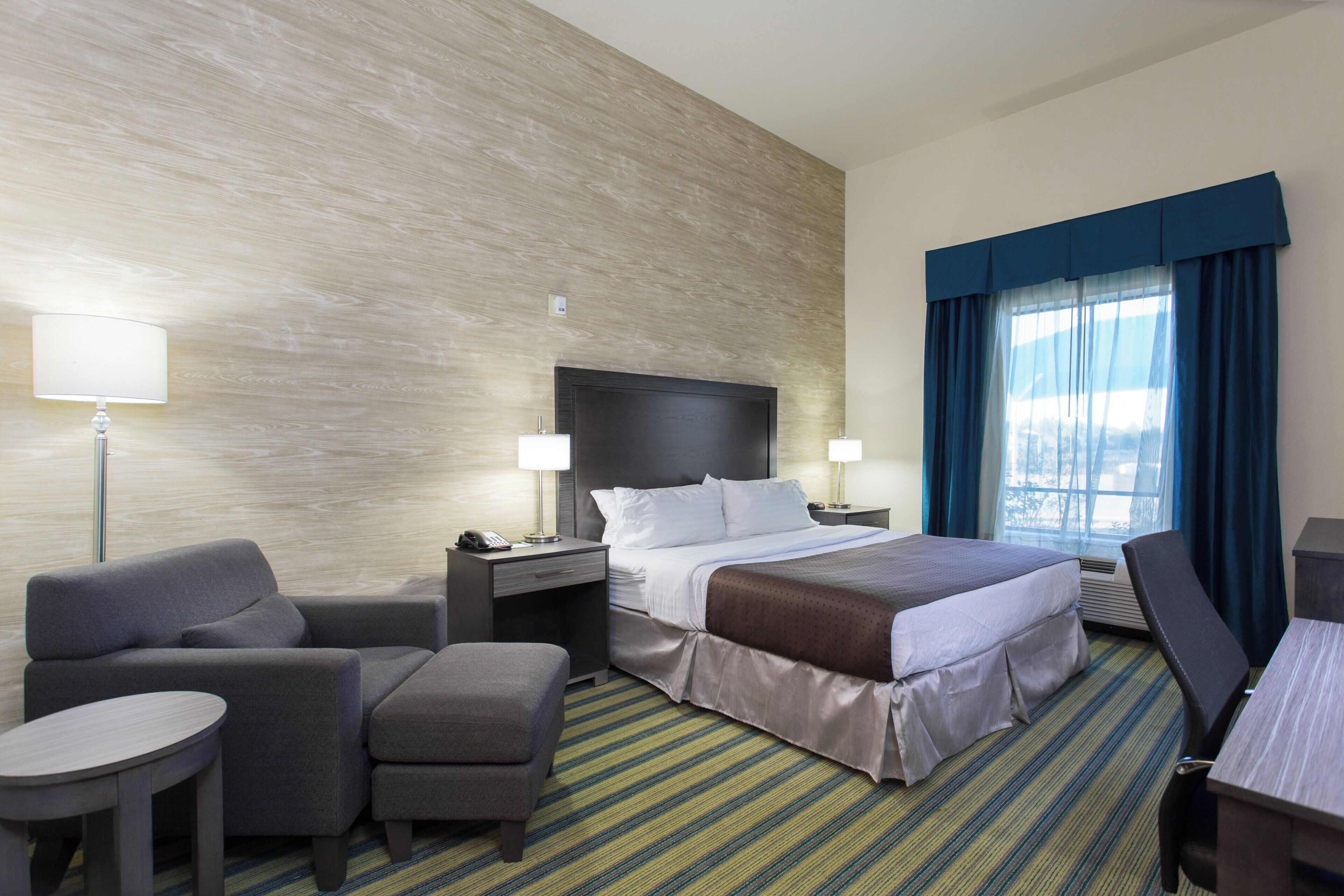 Ein Hotelzimmer mit einem Bett, einem Schreibtisch, einem Stuhl, einem kleinen Tisch und einer Lampe.