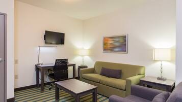 Een hotelkamer met een bureau, stoel, bank en twee lampen.