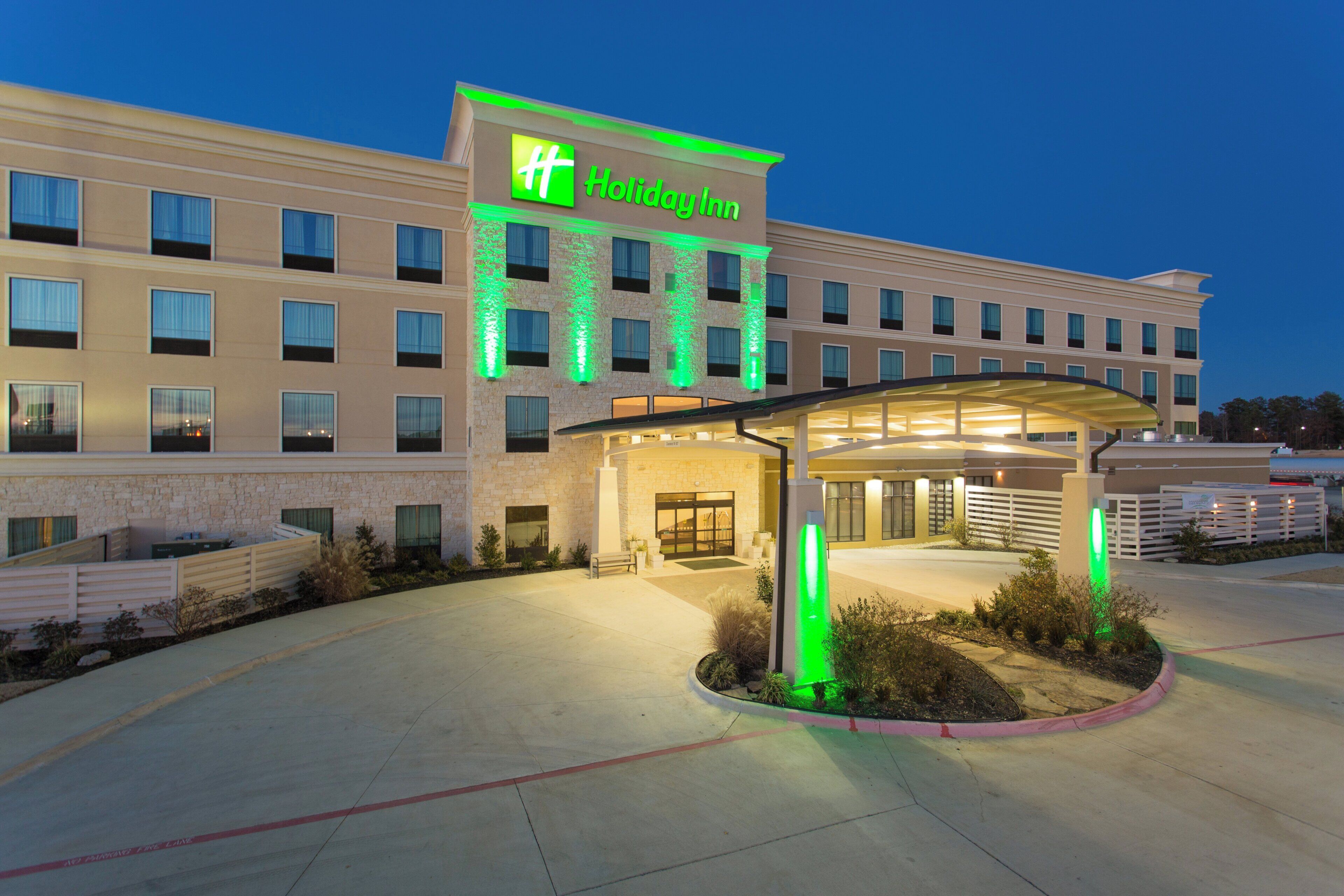Un hotel Holiday Inn con entrada techada y zona ajardinada.