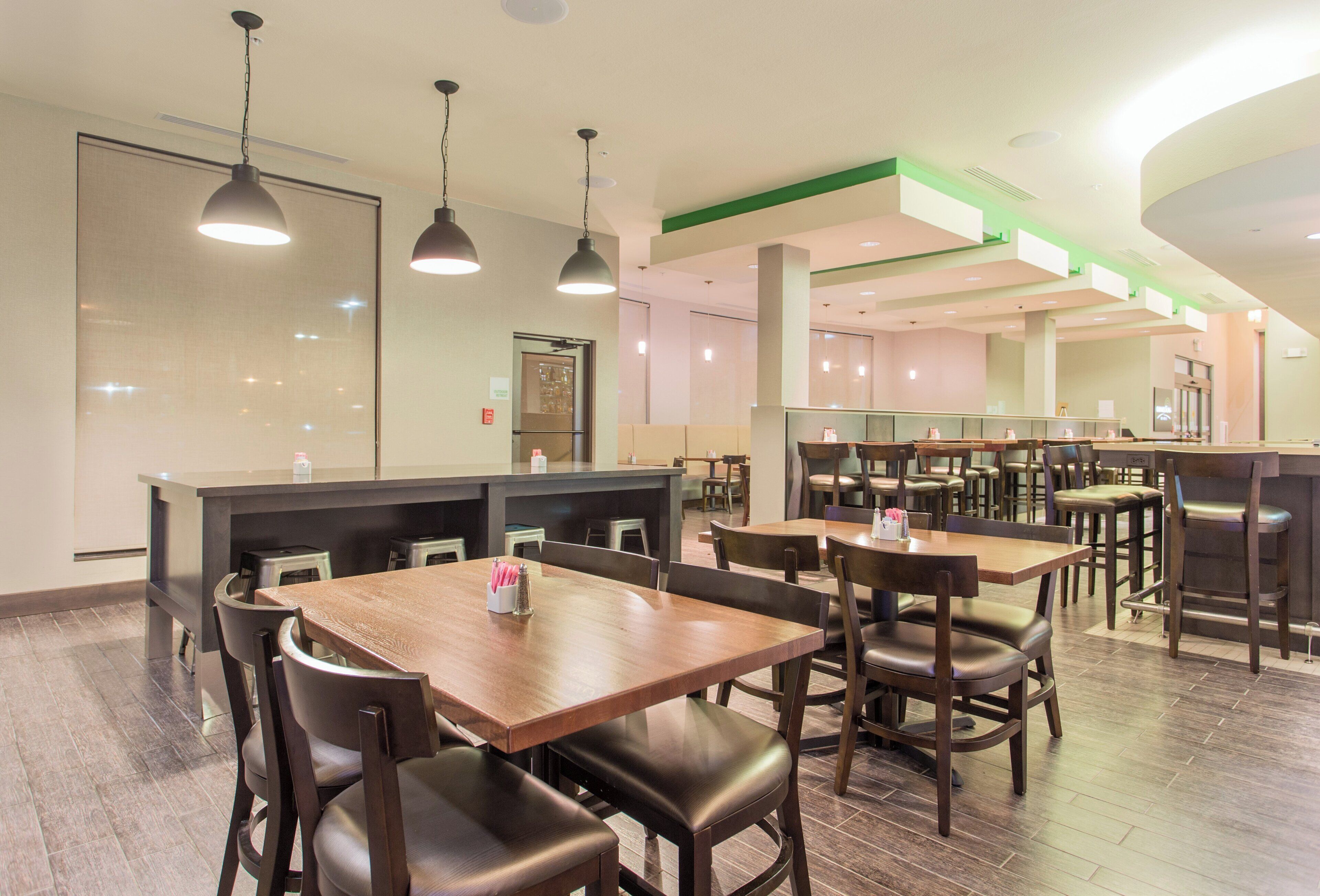 Un restaurant avec des tables et des chaises en bois, un comptoir et des lampes suspendues.