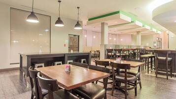 Un restaurant avec des tables et des chaises en bois, un comptoir et des lampes suspendues.