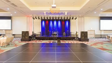 A conference room with a stage, large speakers, and a carpeted floor.