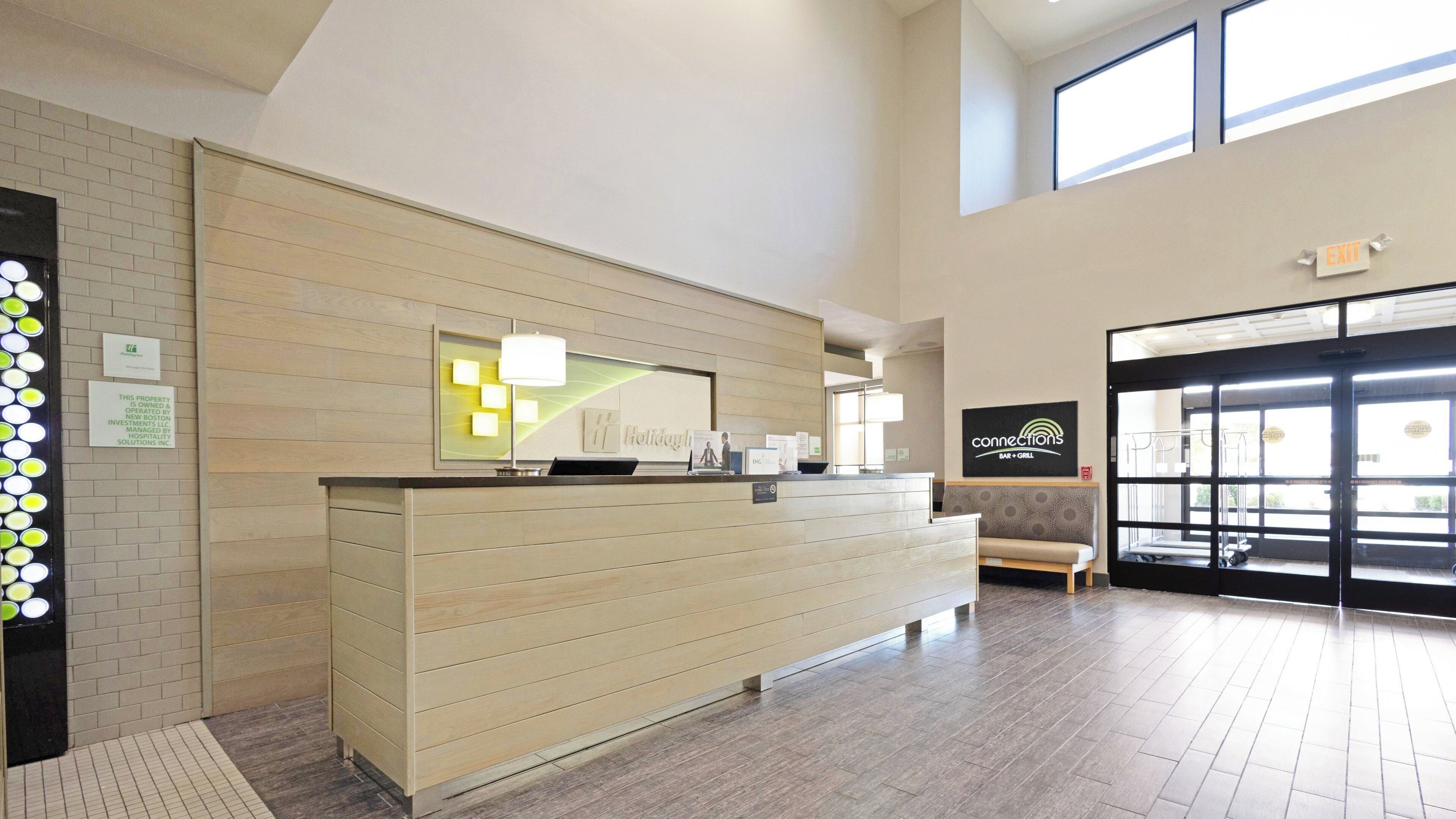 Een receptiebalie met houten afwerking, een bank en een bord met daarop 'connections' bar en grill.