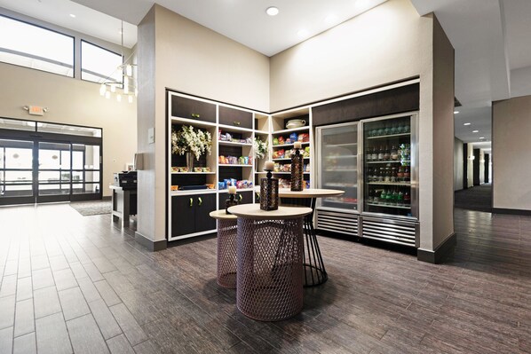 Een moderne hotel lobby met een zithoek, een grote koelkast en een glazen entree.