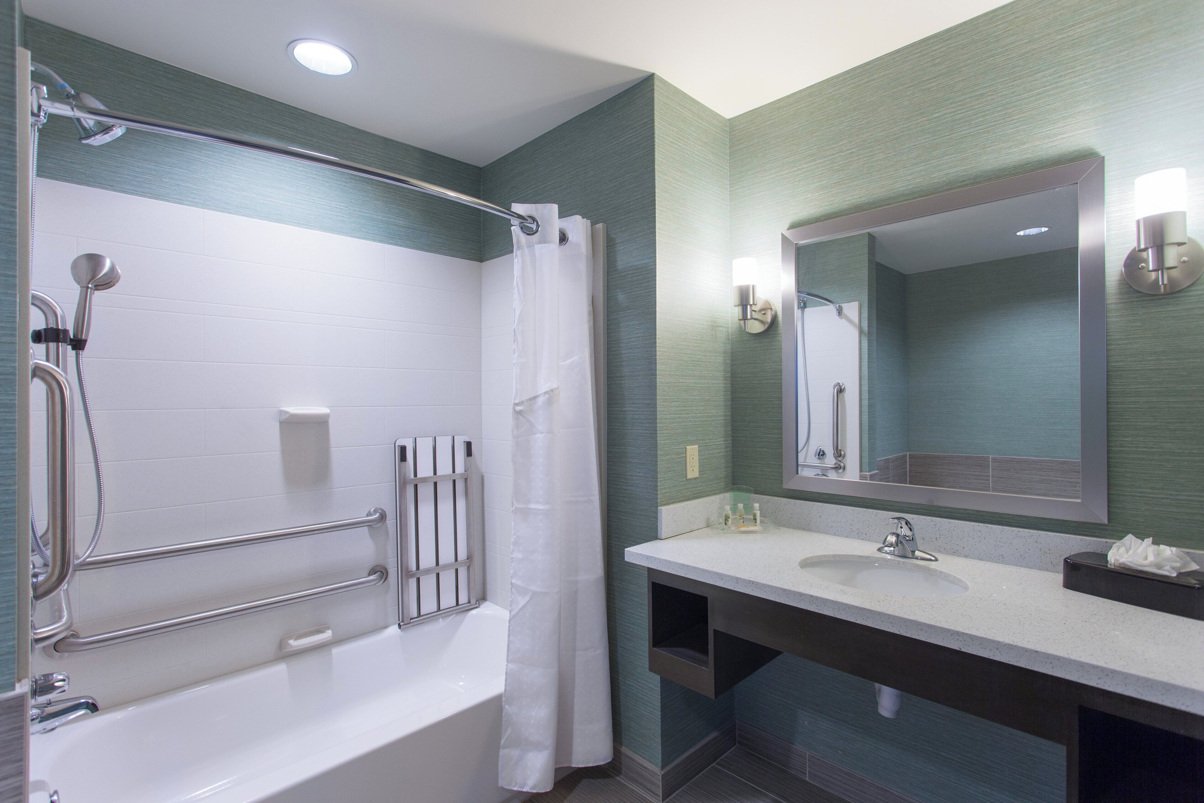 A modern bathroom with a bathtub, a shower, a sink, and a mirror.