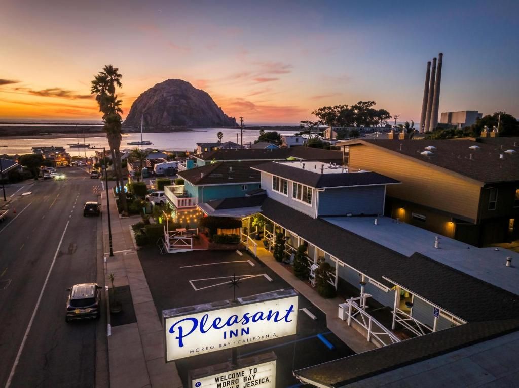 Un motel con un letrero, un estacionamiento y vistas al océano y una montaña al atardecer.