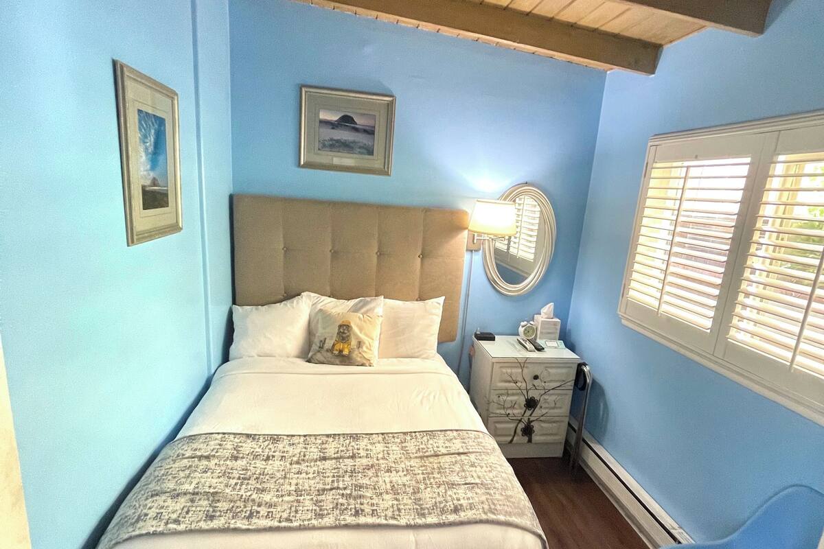 A bedroom with a bed, bedside table, lamp, and a chair.
