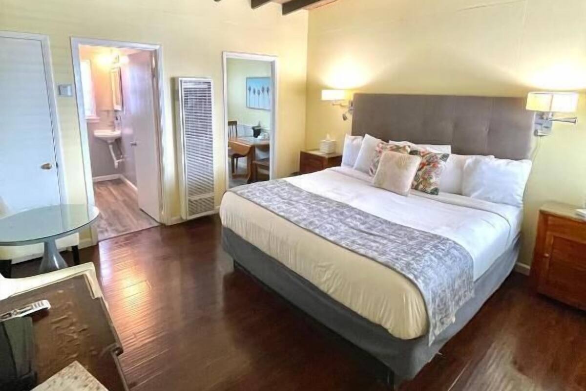 A bedroom with a large bed, wooden flooring, and a sloped ceiling.