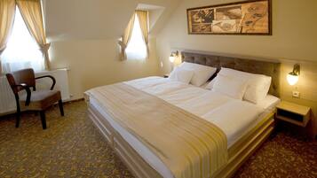 A hotel room with a large bed, a chair, a radiator, and a painting on the wall.