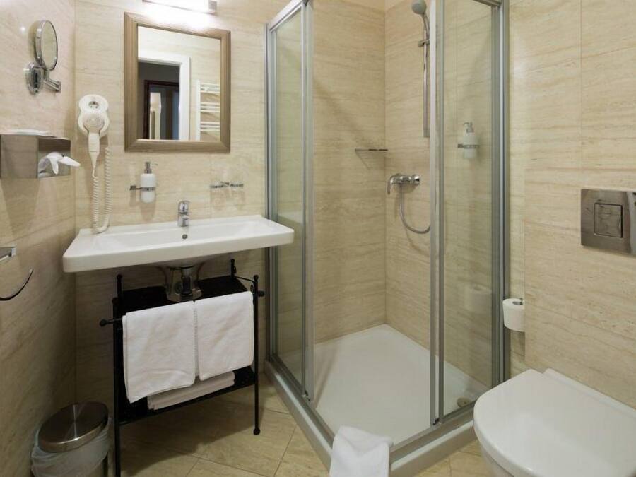 Un baño moderno con ducha de vidrio, un lavabo con espejo y un inodoro.
