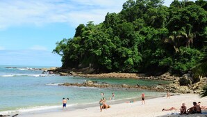 Une plage bordée d’une eau turquoise et limpide, d’une côte rocheuse et d’une végétation luxuriante.