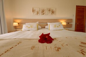 A hotel room with a bed, two bedside lamps, and a wooden door.