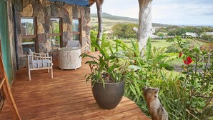 Una terraza de madera con un muro de piedra, un banco y una planta en maceta.