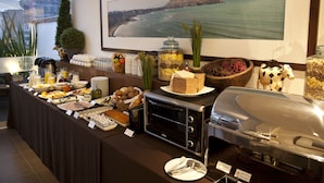 Un buffet garni de divers plats, un four grille-pain et un grand tableau représentant un paysage côtier.