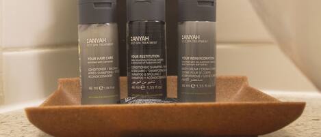Trois flacons de produits de soins de la marque Anyah, présentés sur un plateau marron dans une salle de bain.